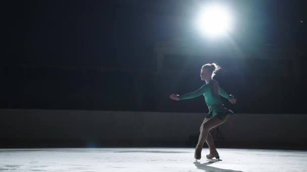 La patineuse effectue un saut avec la rotation d'une triple boucle orteil dans un contre-jour sur un chat de glace. Saut au ralenti en patinage artistique — Video