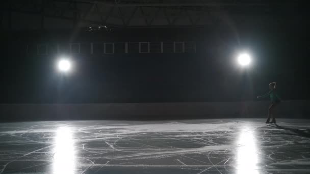 Gadis skater melakukan lompatan dengan rotasi triple toe loop dalam lampu kontra pada kucing es. Slow-motion jump in figure skating — Stok Video