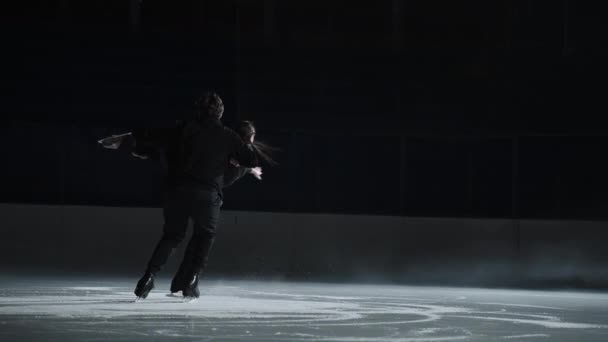 En cámara lenta: una joven pareja de patinadores artísticos está realizando una coreografía de patinaje en pista de hielo antes de comenzar una competición. Concepto de perfección, precisión, libertad, pasión — Vídeos de Stock