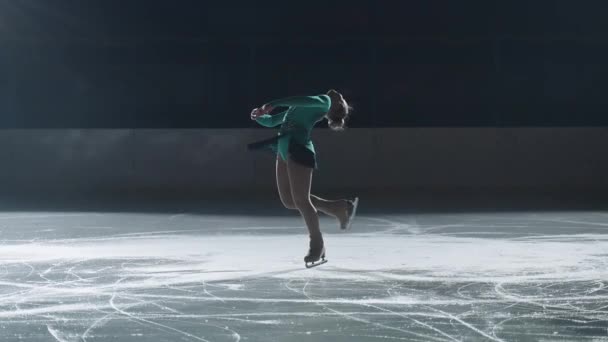 Elegante chica realiza una pirueta en patines, patinador adolescente figura perfecciona la ejecución de rotaciones mientras está de pie en los patines por la noche, se desliza sobre el hielo — Vídeos de Stock