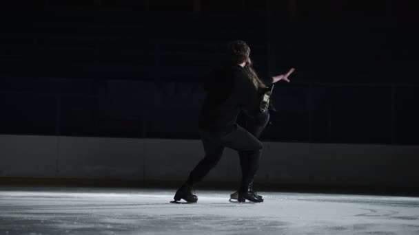 Pair figure skating on the rink. A man and a woman in a counter-light perform elements of the Olympic program together in slow motion — Stock Video