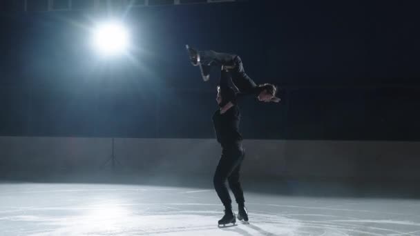 Patinadores profissionais nas contra-voltas um par de homens e mulheres realizar uma rotação, o homem levanta a menina no braço e gira juntos em patins em câmera lenta — Vídeo de Stock