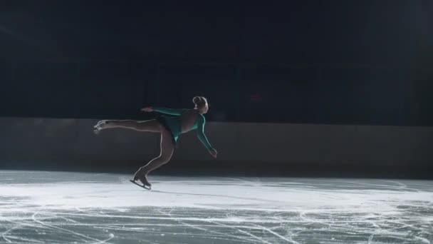 Lindo patinador adolescente realiza rotación de la pierna derecha con inclinación del cuerpo — Vídeo de stock