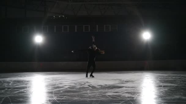 Slow motion: young couple of artistic figure skaters is performing a pair skating choreography on ice rink before start of a competition. Concept of perfection, precision, freedom, passion — Stock Video