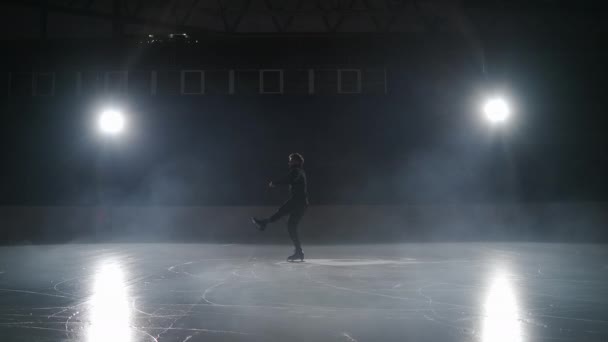 O elemento básico da patinação artística é a rotação em pé. Um patinador artístico masculino profissional realiza uma rotação enquanto está de pé sobre patins. Treinamento único de um atleta em uma pista de patinação indoor. — Vídeo de Stock