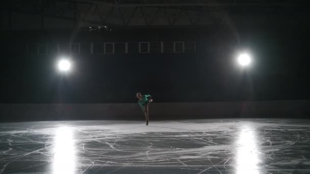 Lassú mozgás: Fiatal női műkorcsolyázó filmes felvétele egy női korcsolyázó koreográfiáját mutatja be a jégpályán a verseny kezdete előtt. A szabadság fogalma — Stock videók