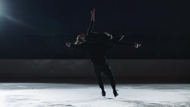 Pair figure skating on the rink. A man and a woman in a counter-light perform elements of the Olympic program together in slow motion — Stock Video
