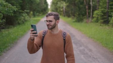 Gözlüklü genç bir adam sakallı bir turist yavaş çekimde yolculuğunun videosunu çekiyor.