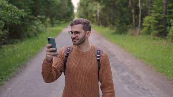 A young man wearing glasses tourist with a beard shoots video on the phone of his journey in slow motion — Stock Video