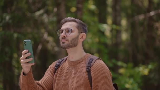 Młody człowiek w okularach, turysta z brodą kręci film przez telefon z podróży w zwolnionym tempie. — Wideo stockowe