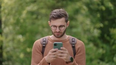 Bir adam ormanda yürüyor ve cep telefonuna bir mesaj yazıyor. Sırt çantalı bir turist yürüyüş sırasında telefonuna bir mesaj basıyor.