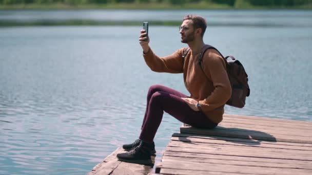 Odważny człowiek robi zdjęcia w lesie jezioro ze smartfonem fotografowania malowniczego krajobrazu przyrody widok tła korzystających wakacje podróży przygoda. Zwolniony ruch — Wideo stockowe
