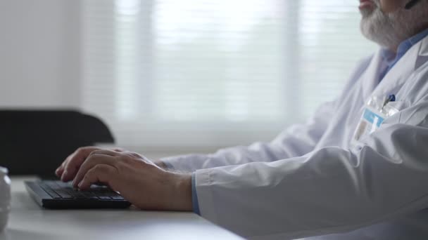 Close up of Caucasian man doctor hands tapping and typing on keyboard sitting in hospital office working at workplace. Healthcare worker fingers texting on computer. Clinic concept — Stock video