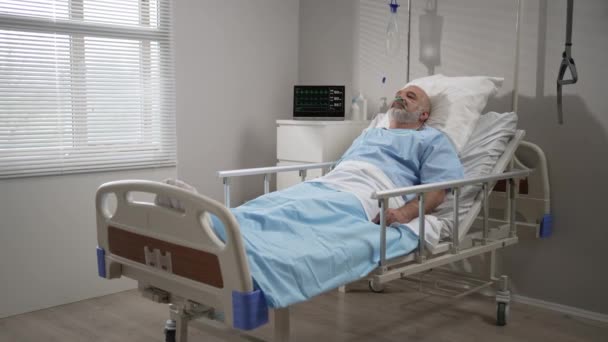 Senior male patient lying in a hospital bed wearing oxygen mask. The device shows the heart rate, pulse, oxygen in the blood, ecg — Video Stock