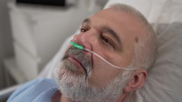 An elderly patient wakes up coming out of a coma. Open your eyes while lying on a bed in a hospital connected In the Hospital Sick Male Patient Sleeps on the Bed, . — Vídeo de Stock