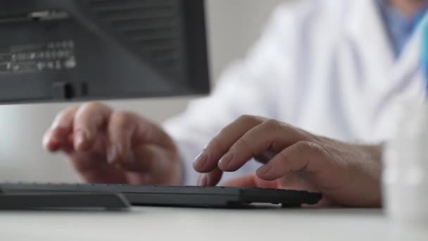 Close up of Caucasian man doctor hands tapping and typing on keyboard sitting in hospital office working at workplace. Healthcare worker fingers texting on computer. Clinic concept — Video
