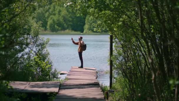 Brave man taking photograph in forest lake with smartphone photographing scenic landscape nature background view enjoying vacation travel adventure. Slow motion — Stock Video