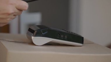 Temassız ödeme nfs sistemini kullanarak genç bir adamın teslimat eli satın almaları için ödeme yapıyor. Genç teslimatçı paketçi müşteri ödeme üniforması ekspres siparişi için telefonla ödeme yapıyor.