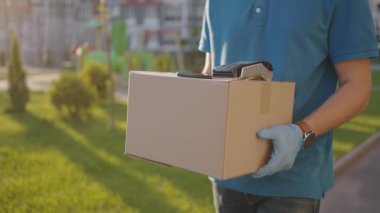 Temassız ödeme nfs sistemini kullanarak genç bir adamın teslimat eli satın almaları için ödeme yapıyor. Genç teslimatçı paketçi müşteri ödeme üniforması ekspres siparişi için telefonla ödeme yapıyor.
