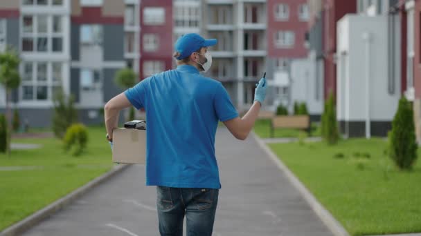 Male courier man is looking for mobile phone to deliver address of food from a shop. Delivery guy navigates in phone in city, searching for shop delivery addresses. Fast delivery — Stock Video