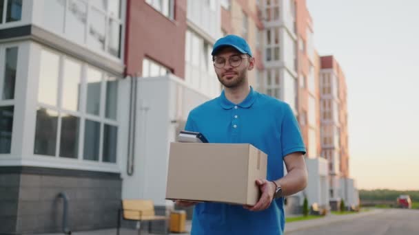 Jovem homem de entrega usando óculos e luvas segurando caixa usar telefone andando em quarentena rua pacote de compras ao ar livre pandemia carteiro auto isolamento câmera lenta — Vídeo de Stock