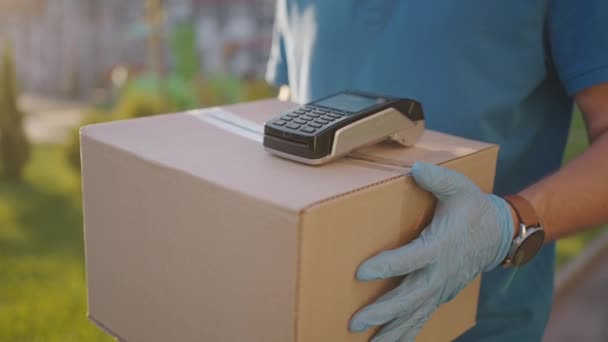 Postbote oder Zusteller tragen kleine Schachteln bei sich, um den Kunden zu Hause kontaktlose nfc-Terminalzahlung zu liefern. — Stockvideo