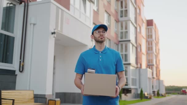 Jeune livreur portant des lunettes et des gants tenant boîte utiliser téléphone marcher sur la rue quarantaine paquet de shopping extérieur pandémie facteur auto isolement ralenti — Video