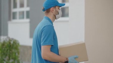 Koruyucu maske ve eldiven takan bir teslimatçı paketi müşteriye verir ve NFC aracılığıyla ücretsiz ödeme alır.
