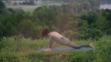 Dağlarda yoga meditasyonu. Yoga yapan bir kız, güneş doğarken uçurumda antrenman yapıyor. Genç atletik kadın dağın tepesinde meditasyon yapıyor. Zen yoga meditasyonu yapıyor.