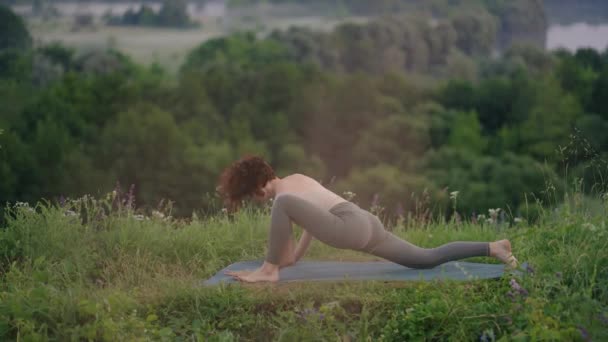 Dağlarda yoga meditasyonu. Yoga yapan bir kız, güneş doğarken uçurumda antrenman yapıyor. Genç atletik kadın dağın tepesinde meditasyon yapıyor. Zen yoga meditasyonu yapıyor. — Stok video