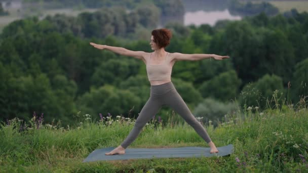 Yoga meditatie in de bergen. Meisje doet yoga poses, heeft training sessie op klif tijdens zonsopgang. Jonge atletische vrouw mediteren op de top van een berg, zen yoga meditatie praktijk in de natuur — Stockvideo