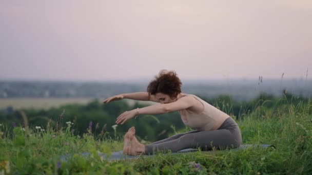 Yoga meditation i bergen. Flicka gör yogaposer, har träningspass på klippan under soluppgången. Ung atletisk kvinna mediterar på toppen av ett berg, zen yoga meditation praxis i naturen — Stockvideo