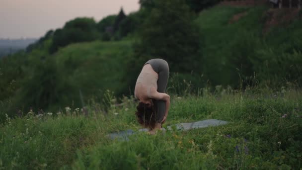 Mulher bonita realizando uma pose de ioga espiritual no topo de uma montanha em câmera lenta, zen bem-estar — Vídeo de Stock