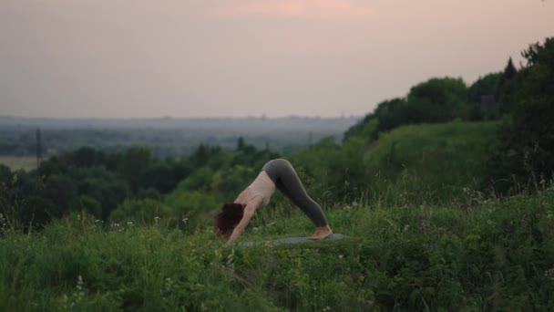 Güzel genç bir kadın, bir dağın tepesinde ruhani yoga pozu veriyor. Ağır çekimde, zen zindeliği içinde. — Stok video