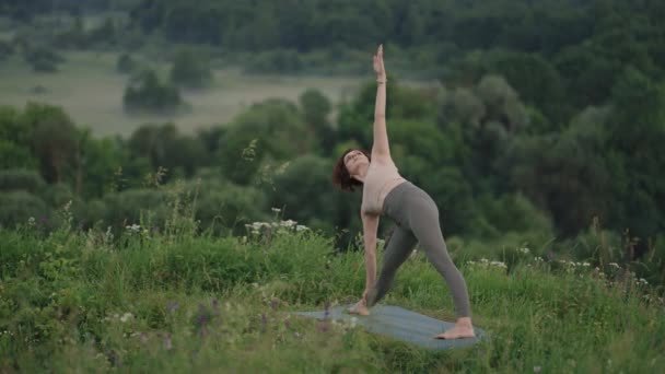 Yoga meditatie in de bergen. Meisje doet yoga poses, heeft training sessie op klif tijdens zonsopgang. Jonge atletische vrouw mediteren op de top van een berg, zen yoga meditatie praktijk in de natuur — Stockvideo