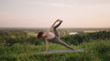 Genç bir kadın sabahın köründe yogayı önceden hazırlıyor. Kadın dağ zirvesinde yoga hareketleri yapıyor. Dağlık alanda dinginlik ve yoga, meditasyon.