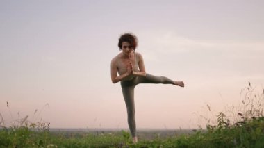 Ağır çekimde, genç bir kadın yoga egzersizlerini dengeleme ve üstte germe yaparak gerçekleştiriyor. Beden ve ruhun sakin ve huzurlu dengesi. Vücut eğilir ve eğilir.