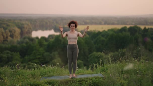 Mujer haciendo yoga en las montañas de Hawaii meditando. Mujer joven está practicando yoga en un hermoso lugar exótico en la cima de una montaña en cámara lenta. Yoga y meditación. — Vídeo de stock