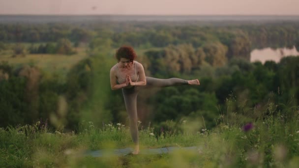 En cámara lenta, una mujer joven realiza ejercicios de yoga realizando equilibrio y estiramiento en la parte superior. Calma y equilibrio pacífico de cuerpo y alma. Cuerpo dobla y dobla — Vídeos de Stock