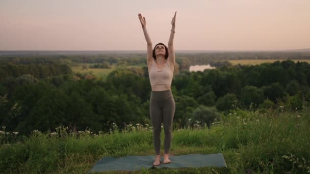 Young woman preforms yoga in mountains in morning light. Woman performs yoga moves on mountain summit. Serenity and yoga practicing at mountain range,meditation — Stock Video