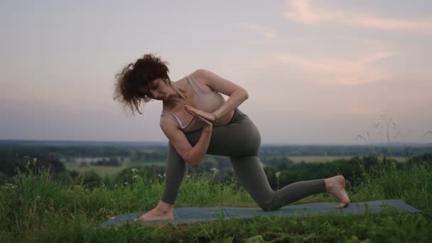 У повільному русі молода жінка виконує вправи з йоги, виконуючи балансування і розтягування зверху. Спокійний і спокійний баланс душі і тіла. Тіло згинається і вигинається — стокове відео