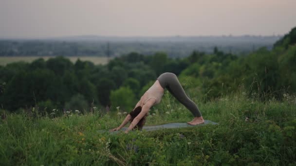 Genç bir kadın sabahın köründe yogayı önceden hazırlıyor. Kadın dağ zirvesinde yoga hareketleri yapıyor. Dağlık alanda dinginlik ve yoga, meditasyon. — Stok video