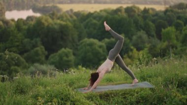 Genç bir kadın sabahın köründe yogayı önceden hazırlıyor. Kadın dağ zirvesinde yoga hareketleri yapıyor. Dağlık alanda dinginlik ve yoga, meditasyon.