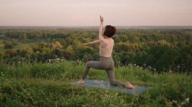 Ağır çekimde, genç bir kadın yoga egzersizlerini dengeleme ve üstte germe yaparak gerçekleştiriyor. Beden ve ruhun sakin ve huzurlu dengesi. Vücut eğilir ve eğilir.