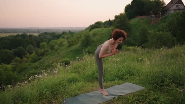 Kvinna som gör yoga i Hawaii bergen mediterar. Ung kvinna övar yoga på vacker exotisk plats på toppen av ett berg i slow motion. Yoga och meditation. — Stockvideo