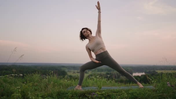 Młoda kobieta preformuje jogę w górach w porannym świetle. Kobieta wykonuje ruchy jogi na szczycie góry. Spokoju i jogi praktykujących na pasmie górskim, medytacji — Wideo stockowe