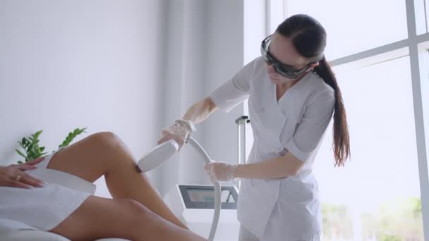 Epilazione laser e cosmetologia nel salone di bellezza. Cosmetologia, spa e depilazione concetto. Procedura di depilazione laser delle gambe femminili. medico in guanti. — Video Stock
