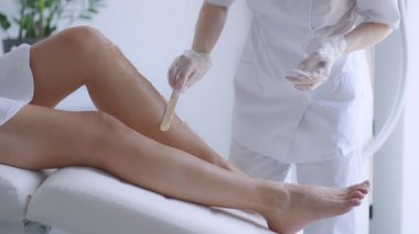 Use a stick to apply a moisturizing gel on the clients legs before laser hair removal on the legs. The doctor prepares his legs for laser hair removal in a beauty salon