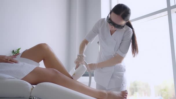 Epilazione laser. Una donna che si fa depilare le gambe con un laser. Salone di bellezza trattamento laser clinica cosmetologia estetista professionista professione concetto di cura del corpo — Video Stock