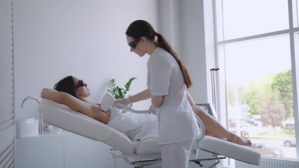 En kvinnlig kosmetolog gör laser hårborttagning av armhålor i en skönhetssalong. Borttagning av hår från armhålorna. Skönhet och ren hud — Stockvideo